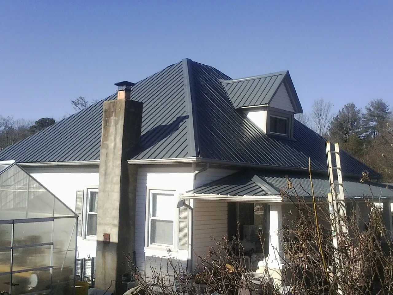 Dark blue standing seam metal roof on a white farmhouse with dormer — Slate & Tile Roof Repair by Roofing Brothers in Chickasha