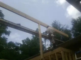 Carpenter setting a ridge beam over a new addition frame in Chickasha