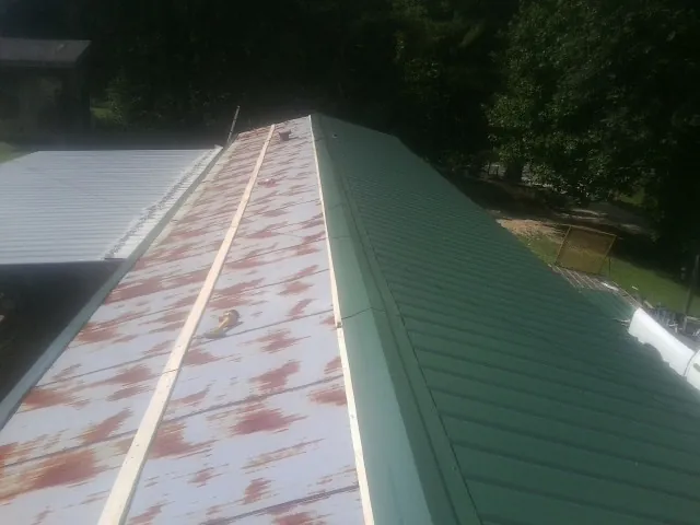 Old rusted panels beside newly installed green metal roofing — Wind Damage Roof Repair by Roofing Brothers in Chickasha