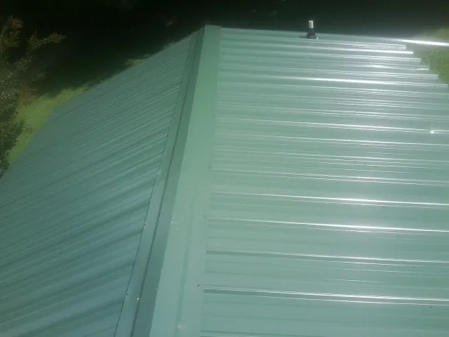 New green metal panels meeting at the ridge of a roof — Flat Roof Repair work by our crew in Chickasha