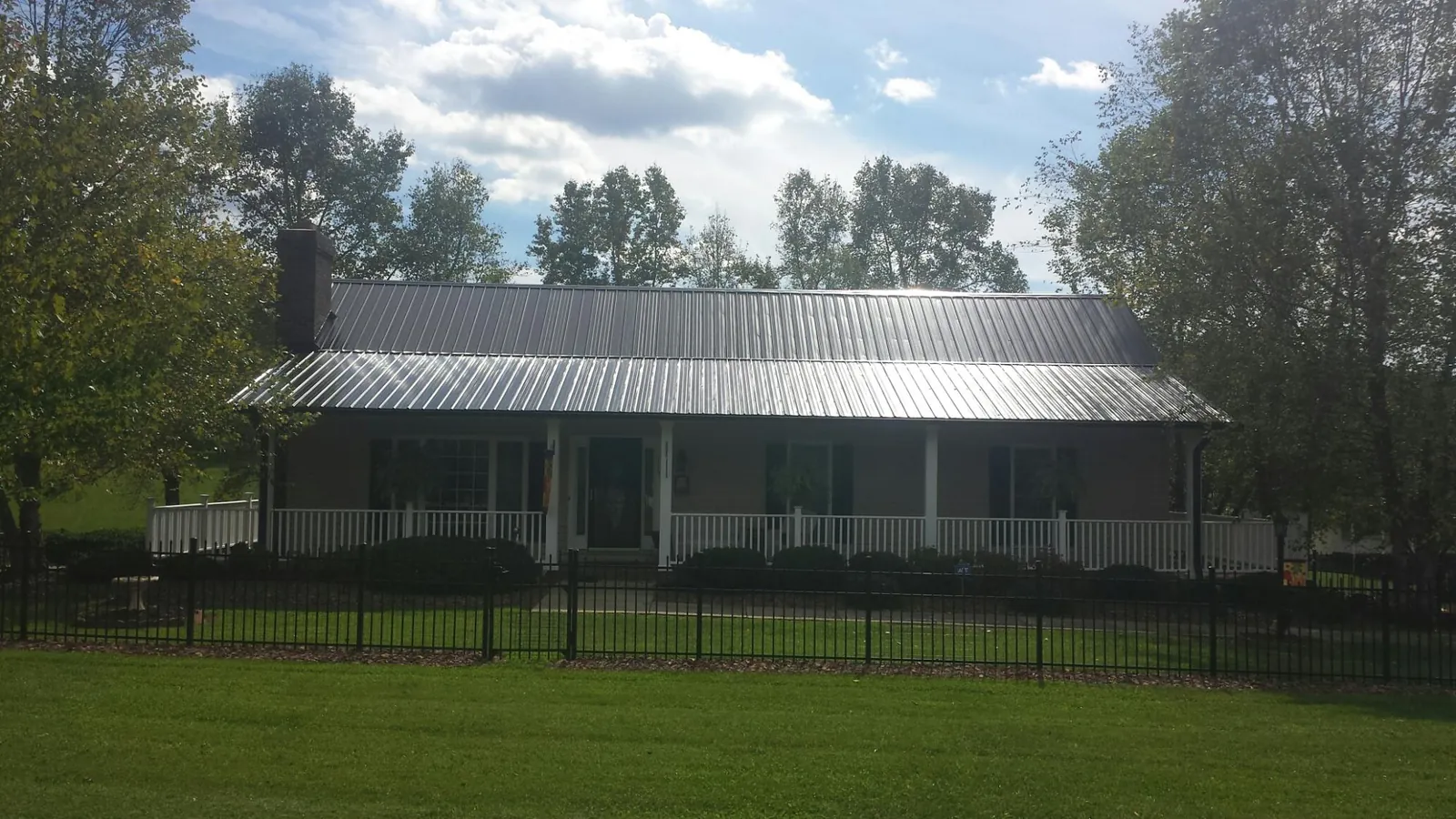 Gray metal roof on a brick ranch with a full width front porch — Gutter Guard Installation work by our crew in Chickasha