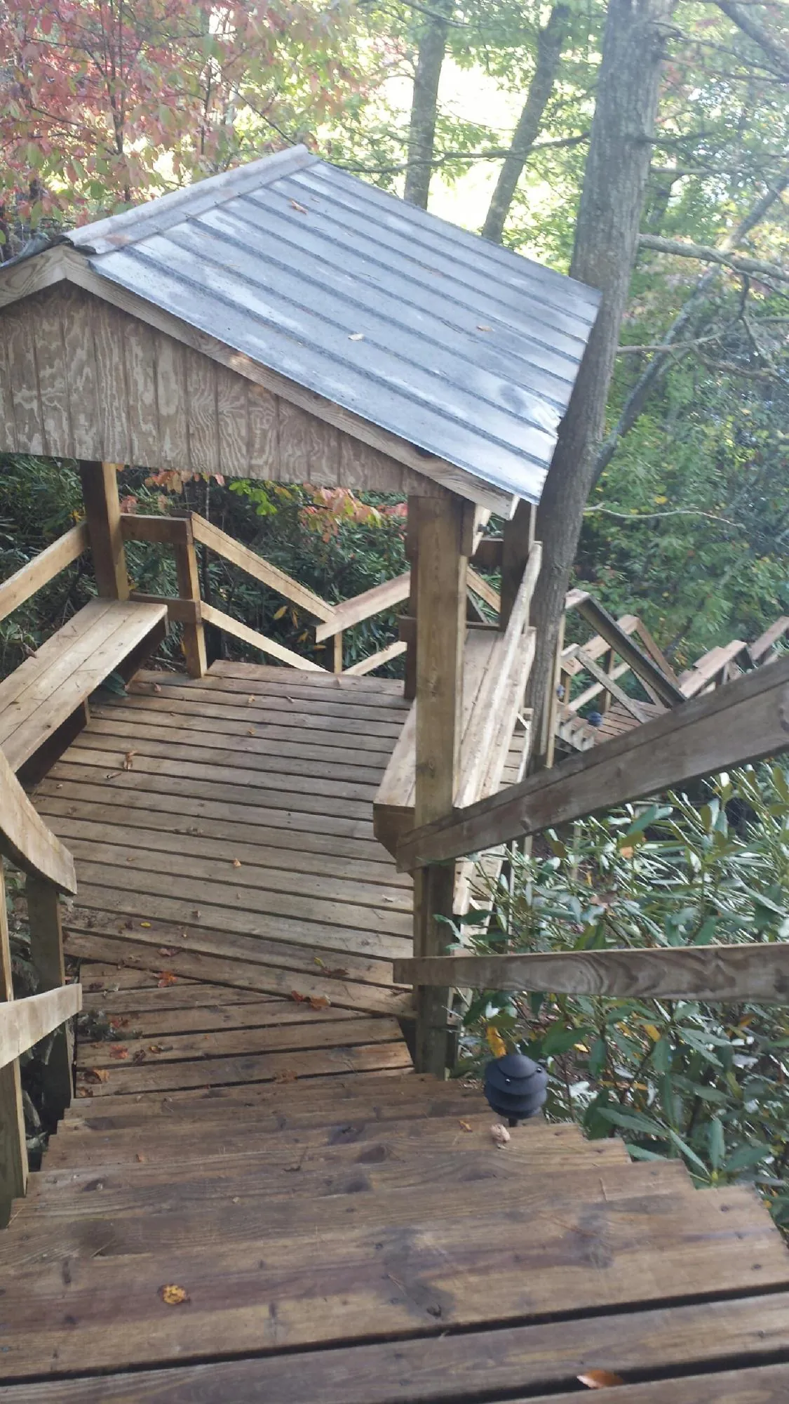 Metal roofed shelter over wooden steps on a wooded walkway — Skylight Repair & Installation work by our crew in Chickasha