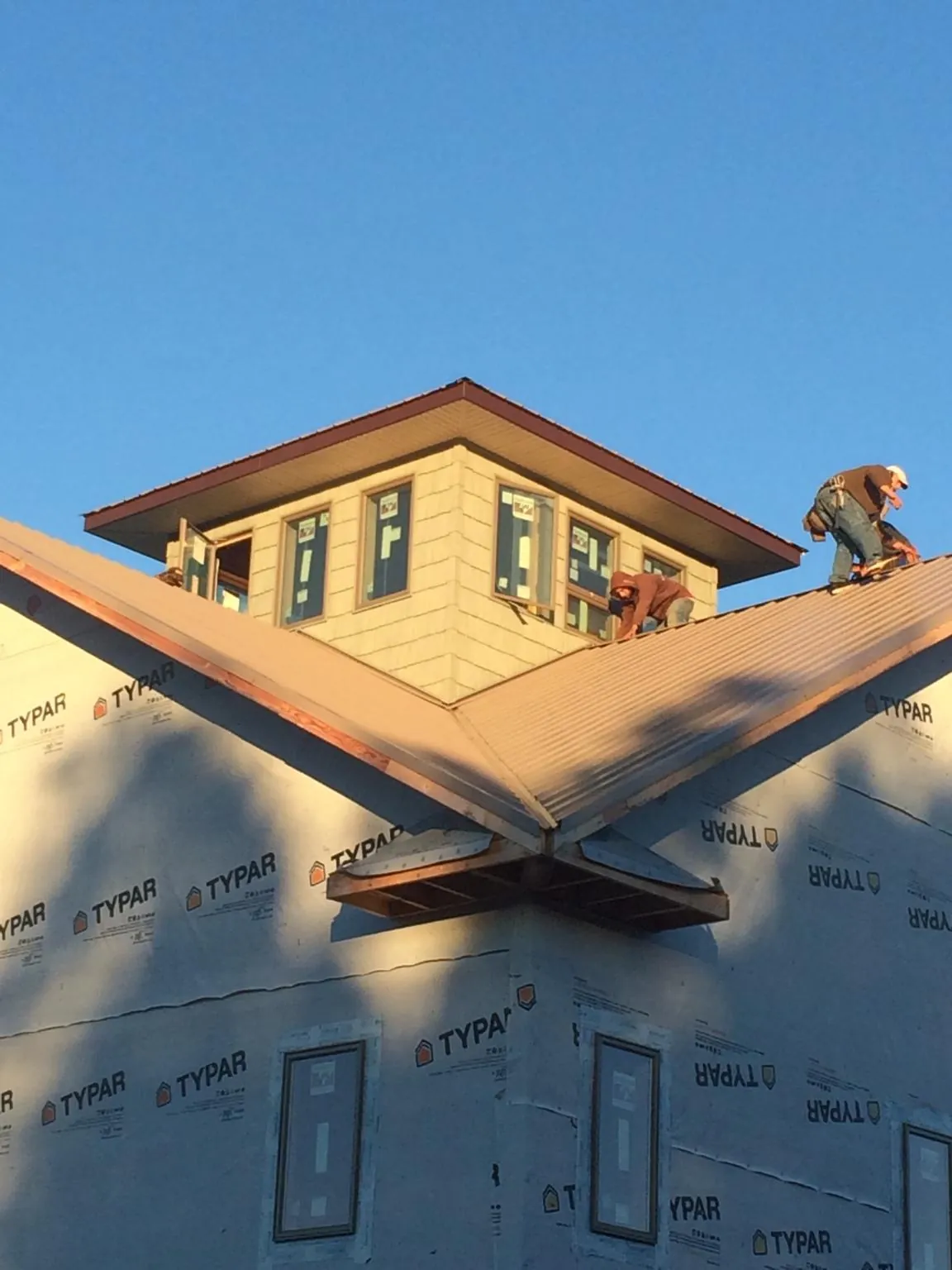 Roofers working around a rooftop cupola on a new metal roof at sunset — Roof Waterproofing in Chickasha by Roofing Brothers
